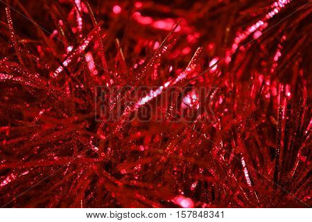 Close-up photo by beautiful red tinsel to background.