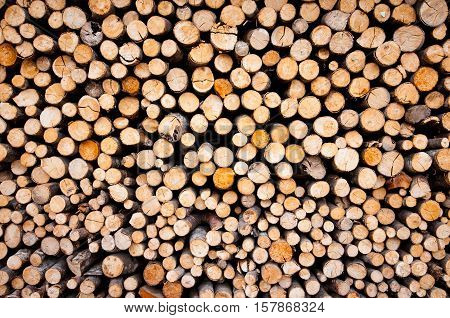 Background of dry chopped firewood logs stacked up on top of each other in a pile