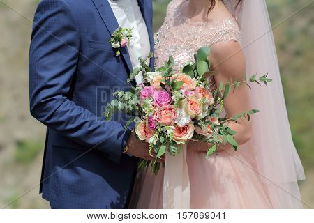 Bride holding a beautiful bridal bouquet. Wedding bouquet of peach roses  single-head pink rose aqua eucalyptus ruscus gypsophila