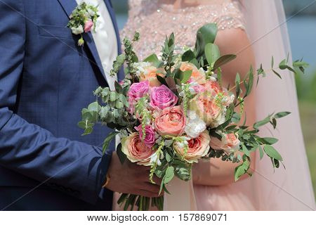 Bride holding a beautiful bridal bouquet. Wedding bouquet of peach roses  single-head pink rose aqua eucalyptus ruscus gypsophila