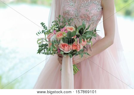 Bride holding a beautiful bridal bouquet. Wedding bouquet of peach roses  single-head pink rose aqua eucalyptus ruscus gypsophila