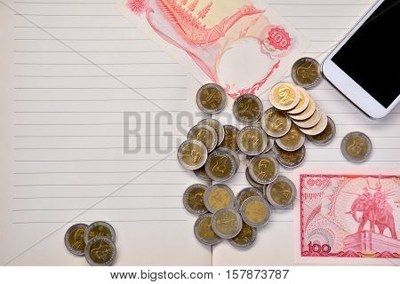 Coins, Smart phone and banknote put on notebook.