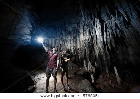 Ungt par at udforske enorme grotte med fakler