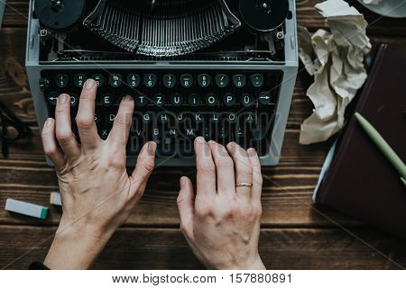 Writer typing with retro writing machine. View from above.