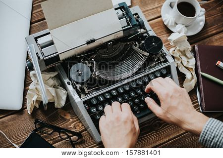 Writer typing with retro writing machine. View from above.
