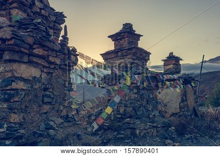 Buddhist stupas connected with praying flags. Sun setting behind Dhaulagiri.