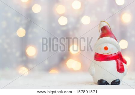 Christmas and new year background - snowman figurine against christmas lights with copy space