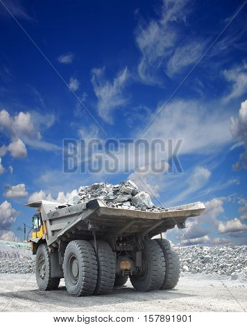 Heavy mining truck loaded with iron ore driving along the opencast on a sunny day
