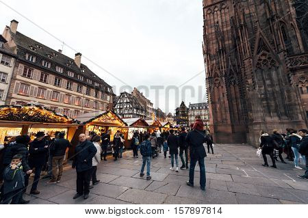 Best Christmas MArket atmosphere in Strasbourg Alsace with people buying gifts drinking mulledwine in central Place near Notre-Dame Cathedral