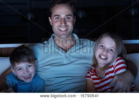 Pai e filhos assistindo o programa na TV sentado no sofá juntos