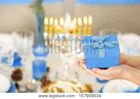 Female hands with present for Hanukkah on blurred background