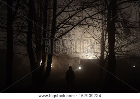 Man standing in front of the house at the night forest