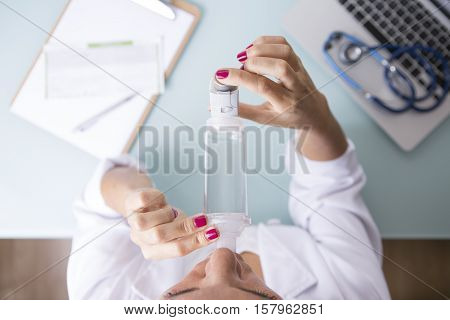 Top view of a close up of a female doctor is inhaling the medicament from the pressurized cartridge inhaler placed on an inhalation chamber on a medical demonstration on her medical desk - Medical respiratory disease