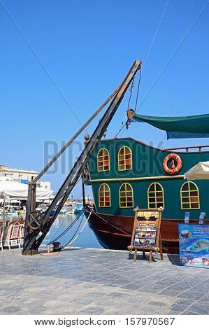 RETHYMNO, CRETE - SEPTEMBER 15, 2016 - View of a Galleon ship and crane in the inner harbour with waterfront restaurants to the rear Rethymno Crete Greece Europe, September 15, 2016.