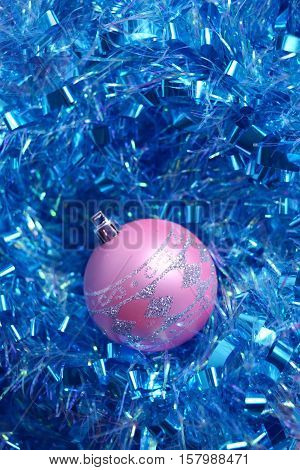 Photo by one pink Christmas ball with ornament in the blue tinsel. Vertical.