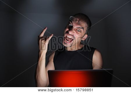Datorhackare med laptop i mörkt rum.