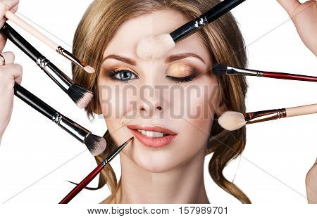 Many hands with cosmetics brushes applying make-up to glamour woman, isolared on white