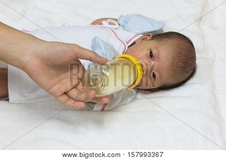 Asian cute new born baby eatting mlik mother in bottle mum feeding on white towel background.