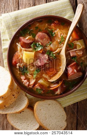 Delicious Soup Of Sauerkraut With Sausages And Vegetables Close-up In A Bowl. Vertical Top View