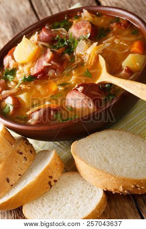 Delicious Soup Of Sauerkraut With Sausages And Vegetables Close-up In A Bowl. Vertical