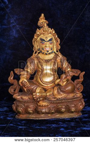 Buddha Golden Jambhala Statue On A Dark Texture Background; The Buddha Of Wealth And Abundance With 