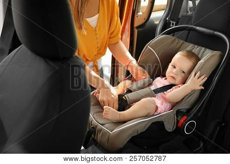 Mother Fastening Baby To Child Safety Seat Inside Of Car