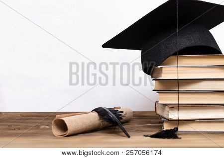Stack Of Books, Graduate Cap, Diploma And Fether Pen On The School Desk Isolated On White Background
