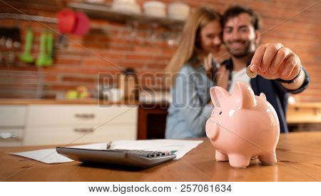 Happy Couple Inserting Coin In Piggybank