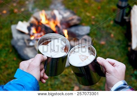 Wanderlust And Travel Concept. Metal Cups With Hot Chocolate And Marshmallows. Fire On Background. A