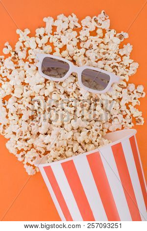 Popcorn Pouring From A Paper Bowl To A Orange Background, And 3d Glasses For Watching The Movie, A T