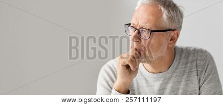 old age, problem and people concept - close up of senior man in glasses thinking
