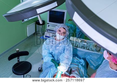 Cosmetic Liposuction Surgery In Actual Operating Room, Group Of Surgeons Working With Cannula