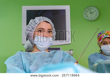 Cosmetic Liposuction Surgery In Actual Operating Room, Group Of Surgeons Working With Cannula