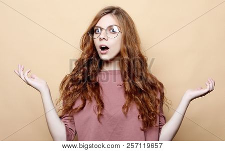 Surprised terrified female gestures with uncertainty, stares at camera, puzzled as doesn`t know anwser on tricky question