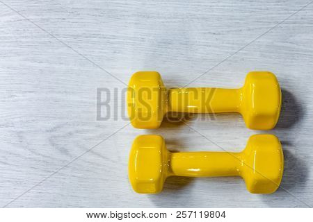 Yellow Modern Dumbbells On A Wooden Floor