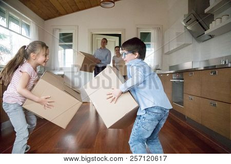 Excited Kids Having Fun Bringing In Boxes To New House