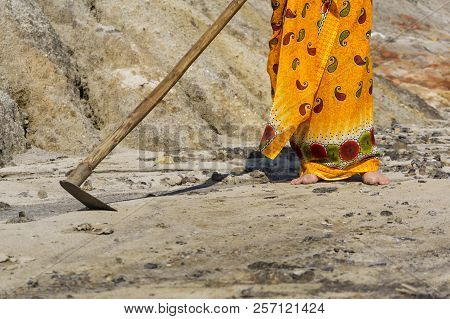 A Woman In An Ethnic Bright Dress With A Primitive Hoe Trying To Cultivate Dry Hard Barren Sandy Ear