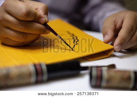 Book Binder Hand Painting A Calligraphic Pattern On The Yellow Cover Of A Hardcover Book In His Work