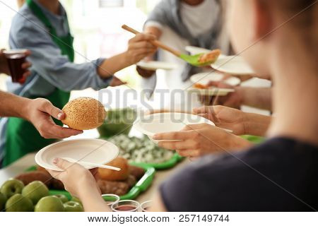 Volunteers Serving Food For Poor People Indoors