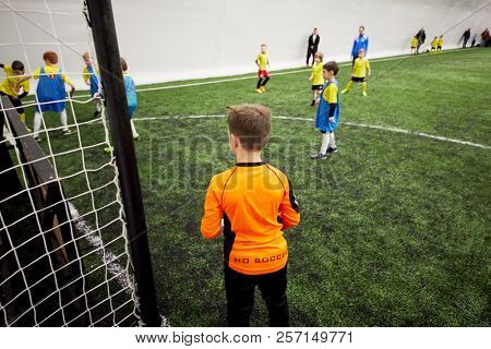 MOSCOW, RUSSIA - JAN 27, 2018: Goalkeeper at goal post and players during children sport clubs cup soccer game at indoor sports ground of Krasnaya Presnya stadium.