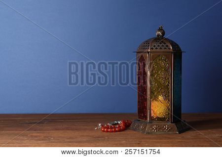 Muslim Lamp With Candle And Misbaha On Wooden Table. Fanous As Ramadan Symbol
