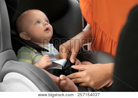 Mother Fastening Baby To Child Safety Seat Inside Of Car