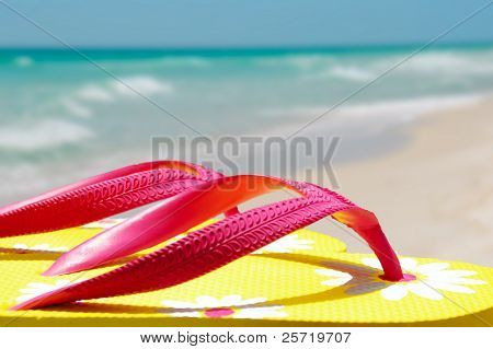 รองเท้า flipflop สีเหลือง และสีชมพูบนฝั่งชายหาด
