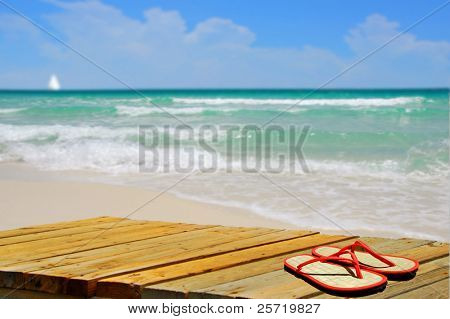Beautiful deserted beach with colorful flipflops on pier
