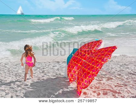 Ragazza in esecuzione di ombrelloni con barca a vela in lontananza con di bella spiaggia surf