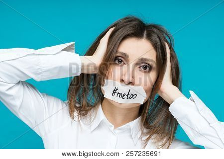 Closeup Portrait Of Young Woman In Fright Clings To Her Head With Her Hands, The Mouth Is Sealed Wit
