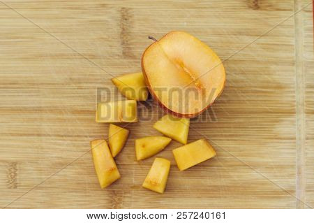 A Chopped Amigo Pluot Next To One Half Piece On A Wood Cutting Board