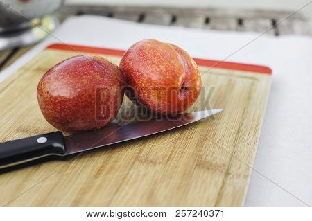 Two Fresh Amigo Pluots On Top Of A Cutting Board With A Knife