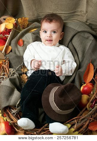 autumn concept - child boy lie on yellow leaves with fruits and vegatbles, red apples and pumpkins