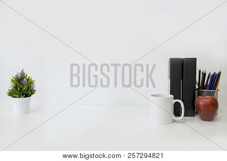 Mockup Table With Plant Decorate, Cup Of Coffee, Book,red Apple And Jar Of Pencil On White Table And